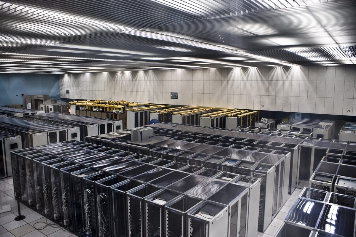 Rows of server racks in a large data centre hall seen from above